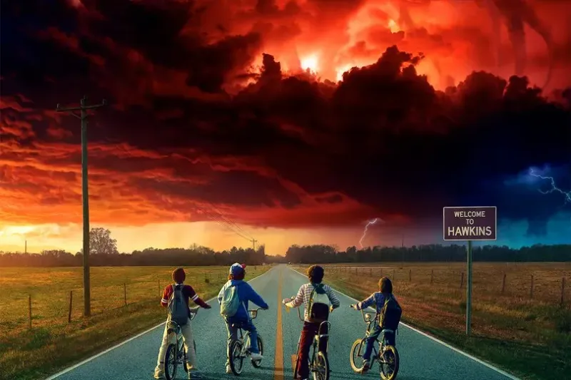 The Stranger Things kids sit on their bikes on an open road, looking at ominous red clouds