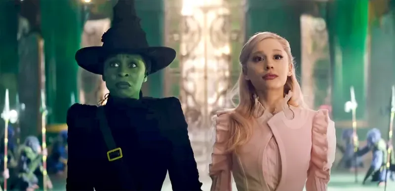 Elphaba and Glinda stand next to each other, holding hands