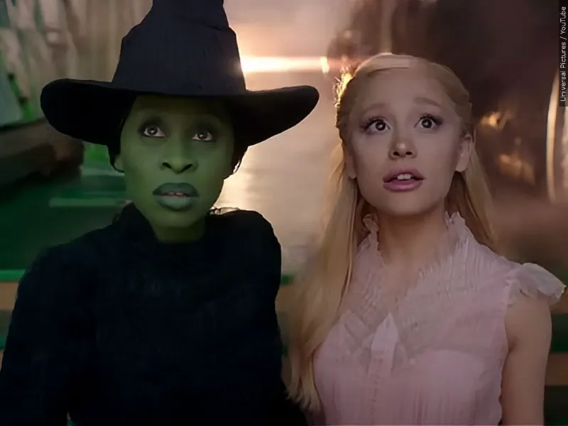 Elphaba and Glinda stand next to each other, holding hands