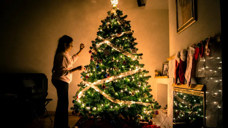A woman decorates a beautiful sparkling Christmas tree